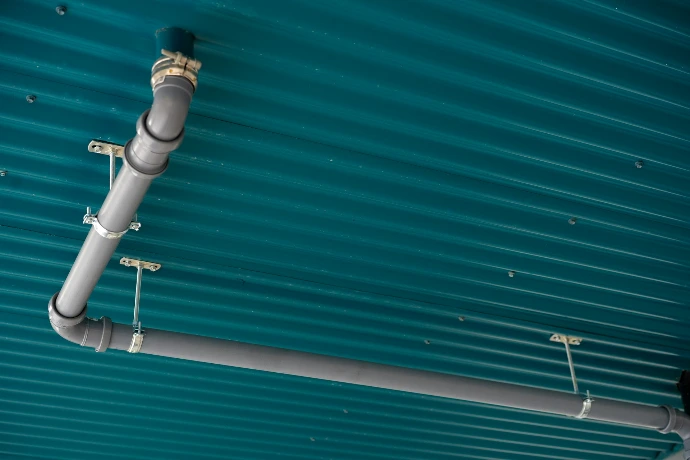 Pipes are installed on a teal, ribbed ceiling.